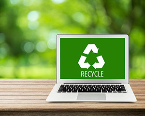 Laptop on a desk showing a green recycle icon