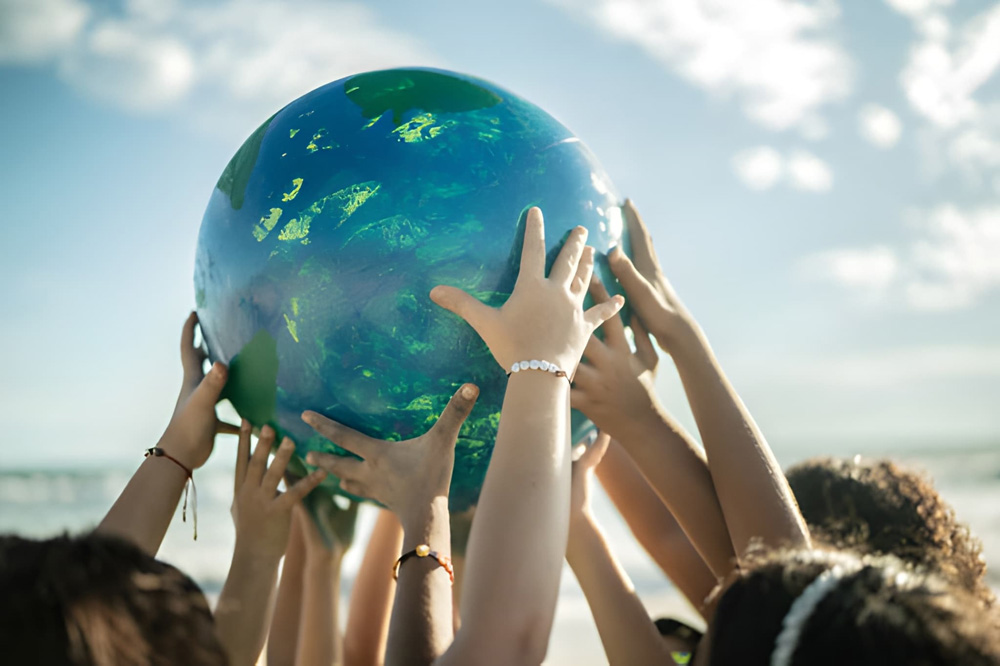 Group of people holding a globe together outdoors.