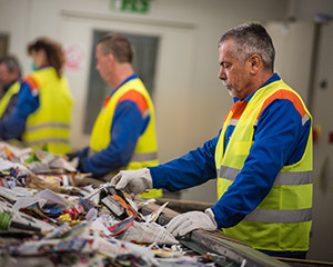 Workers in safety vests sorting through waste