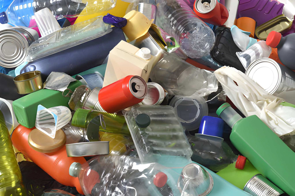 Mixed plastic bottles, containers, and aluminum cans piled together for disposal.