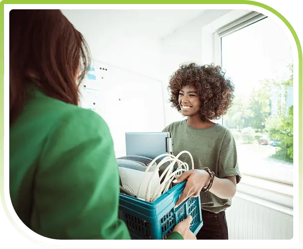 Two women carrying a crate of old electronics.