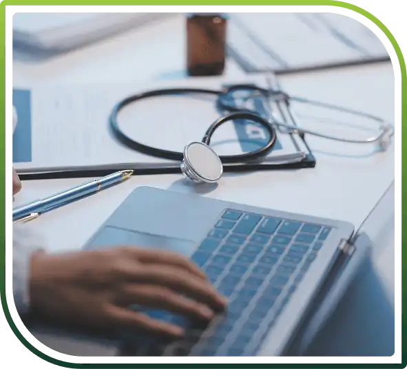 Healthcare professional using a laptop with medical documents and stethoscope