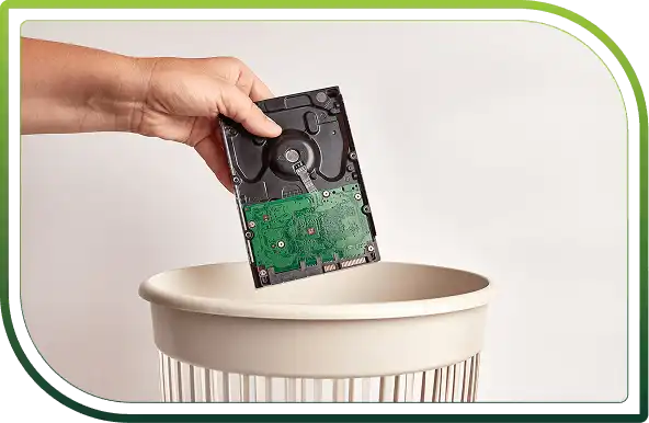 Hand disposing of a hard drive into a secure bin, representing responsible data destruction and IT asset disposal services.