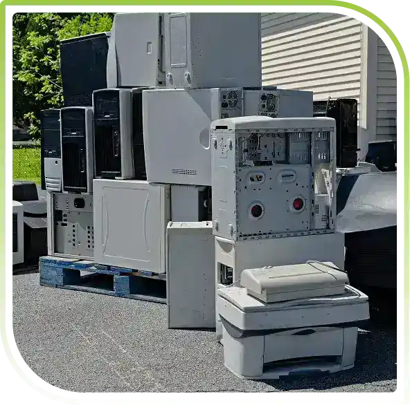 Stacked surplus computer equipment and office hardware outdoors, representing large-scale IT asset liquidation and secure ITAD ser
