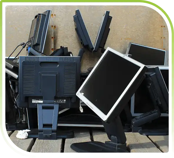 Pile of discarded computer monitors stacked together, representing bulk electronics disposal and responsible recycling services.